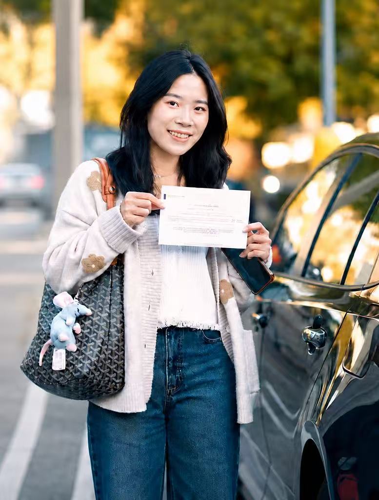 A successful Yohon student showing her license beside a car